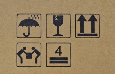 Warning labels on cardboard box silhouette shapes umbrella glass arrows, this way up fragile keep dry height stack limit two person carry transportation logistics instructions.