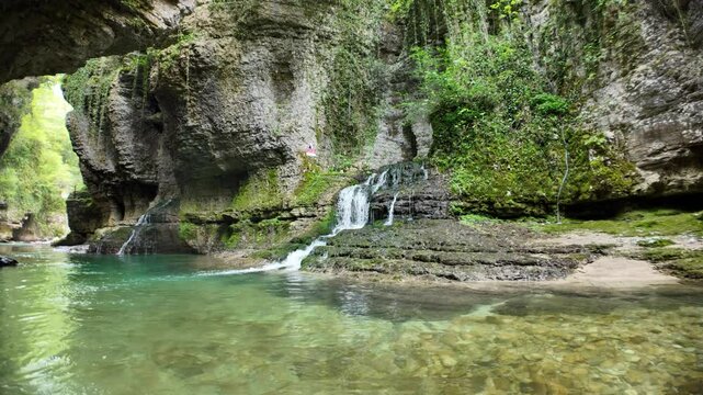 Crystal clear water flowing through Martvili Canyon in Georgia, with waterfalls cascading down mossy rocks into the Abasha River, creating a picturesque natural landscape