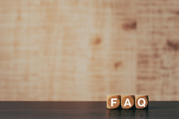 There is wood cube with the word FAQ. It is an abbreviation for Frequently Asked Questions as...