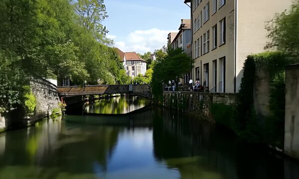 Canal in a European Town with Stone Buildings Lush Trees and Clear Blue Sky Reflecting in the Water on a Sunny Day