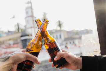 Hands holding beer bottles, clinking them.