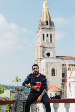 A man sitting in fron of a stone church.