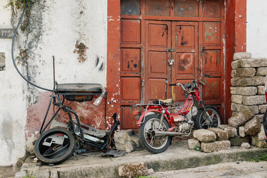 Two old motorcycles parked next to a brick wall.