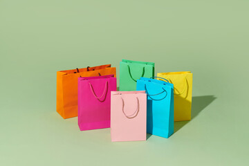 Colourful paper shopping bags isolated on green