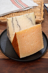 Two pieces of Spanish hard cheese, cow and sheep curado, manchego, goat cheese with added black truffle mushrooms and very old anejo tostado cheese
