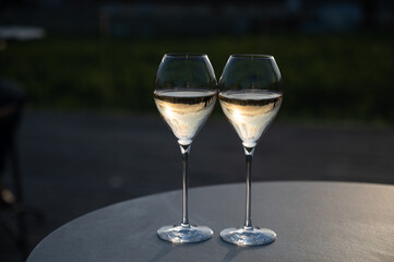 Glasses of white sparkling wine brut, grand reserve, champagne on green hilly vineyards in old wine making grand cru Ay-Champagne village in Vallee de la Marne, Champagne, France