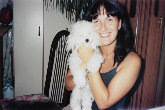 Smiling woman with poodle in arms