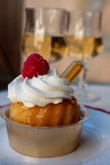 French cuisine, fresh baked baba au rum cake with chantilly cream, sweet dessert with rum and glasses of champagne wine close up