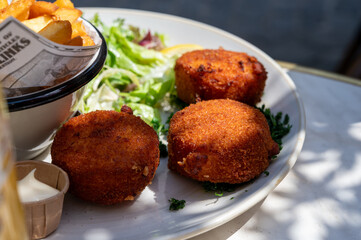 Lunch in cafe with vegetarian cheese and green asparagus croquettes served with fresh salad and french fries potato in Bruges, Belgium