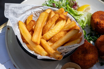 Lunch in cafe with vegetarian cheese and green asparagus croquettes served with fresh salad and french fries potato in Bruges, Belgium