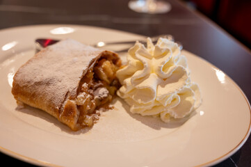 Austrian desserts, piece of apple strudel with whipped cream served in traditional bakery cafe in Vienna, close up