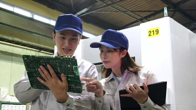 工場でタブレットを使って製品を検査する男女作業員