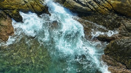Naklejka premium The aerial shot captures the epic crash of waves, slowing down the intense impact as water explodes against the rugged coastline, revealing the ocean’s vast, relentless energy. 