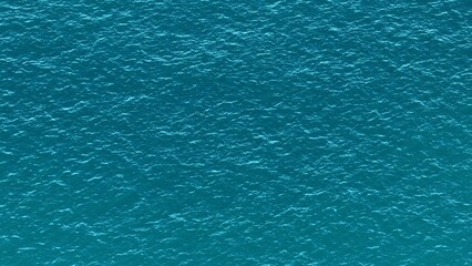 A bird&rsquo;s-eye view highlights the turquoise ocean, with gentle waves flowing across the surface, forming a soothing, patterned texture that captures the peacefulness of the tropical sea.
