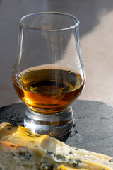 Whiskey and cheese pairing, tasting whisky glass and plate with sliced blue stilton and blue shropshire cheeses, Great Britain food and drink