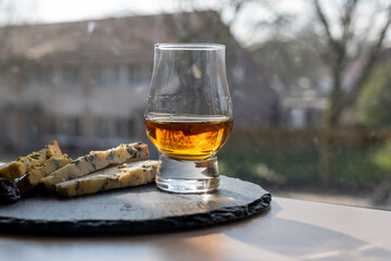 Whiskey and cheese pairing, tasting whisky glass and plate with sliced blue stilton and blue shropshire cheeses, Great Britain food and drink