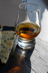 Whiskey and cheese pairing, tasting whisky glass and plate with sliced blue stilton and blue shropshire cheeses, Great Britain food and drink