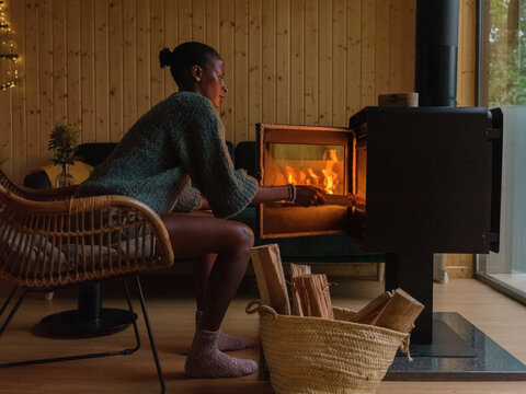 Woman loading firewood into fireplace