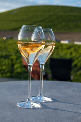 Glasses of white sparkling wine brut, grand reserve, champagne on green hilly vineyards in old wine making grand cru Ay-Champagne village in Vallee de la Marne, Champagne, France