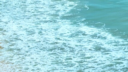 Obraz premium The ocean’s gentle waves break on the shoreline, their white foam swirling with each movement. This peaceful, natural scene evokes the calmness and beauty of the sea. Thailand. 