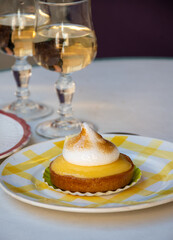 One French lemon tart or tartalette with white eggs meringue and glasses with champange sparkling wine