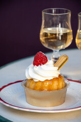 French cuisine, fresh baked baba au rum cake with chantilly cream, sweet dessert with rum and glasses of champagne wine close up