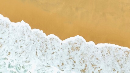 The captivating motion of sea waves crashes onto the shore, with the white foam contrasting against the golden beach, creating a beautiful natural scene of harmony and movement.
