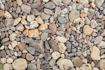 Small natural stone with various shapes and neutral colors covering ground, creating textured and...