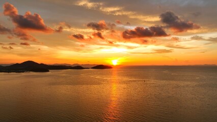 An aerial shot capturing a breathtaking sunset over the sea. The vibrant sky, filled with warm colors, reflects off the calm water, creating a peaceful and beautiful landscape. Thailand.
