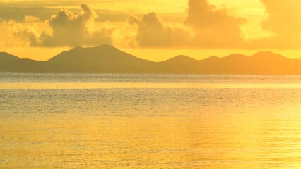 An aerial shot reveals the stunning beauty of a tranquil seascape at sunset, with the golden hues...
