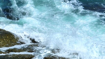 A powerful aerial view of waves crashing on rocks, sending spray into the air, capturing the movement and energy of the ocean, perfect for dynamic coastal and nature themes. Phuket, Thailand.
