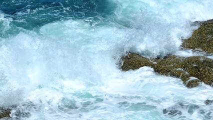 Obraz premium A close-up view of ocean waves breaking on rocks, with water splashing in the air, conveying the raw power and beauty of the sea, ideal for dynamic beach and coastal scenes. Phuket, Thailand. 