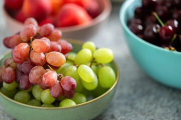Grapes in a bowl surrounded by various fruit bowls on table
