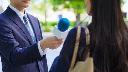 街頭インタビューをする男性レポーター