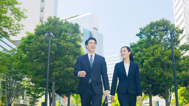 歩く、ビジネスパーソン、チームワーク、パートナー、スタート、爽やか、屋外、新緑、歩道、歩行者、都市、公園、笑顔、自然、スーツ、ビジネスマン、ビジネスウーマン、女性、男性、日本人、仕事、働く、談笑、会話、話す、相棒、上司、部下、同僚、30代、ポジティブ、元気、ビジネス、就職、転職、前進、成長、目標、挑戦、チャレンジ、都会、会社員、サラリーマン、指導、経営、訪問、営業、外回り、人物