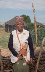 village rural ,portrait of african woman, in front of a house with thatched roof , countryside living,