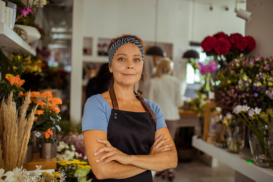 Confident female florist standing in flower shop with arms crossed and smiling