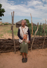 village rural ,portrait of african woman, in front of a house with thatched roof , countryside living,