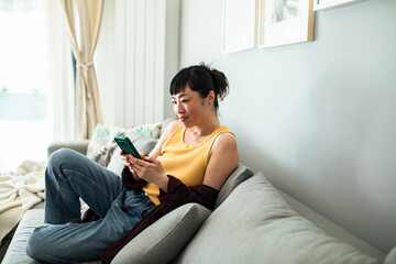 Smiling woman relaxing on couch having video call on smartphone
