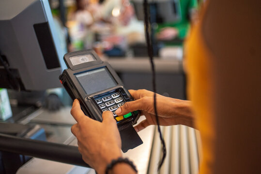 Anonymous hand paying supermarket cashier on card device