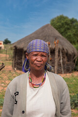village rural ,portrait of african old woman, in front of a house with thatched roof , countryside living,