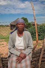 village rural ,portrait of african old woman, in front of a house with thatched roof , countryside living,