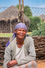 village rural ,portrait of african old woman, in front of a house with thatched roof , countryside living,
