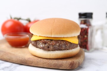 Tasty cheeseburger on white marble table, closeup