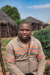 village rural ,portrait of african man, in front of a house with thatched roof , countryside living,