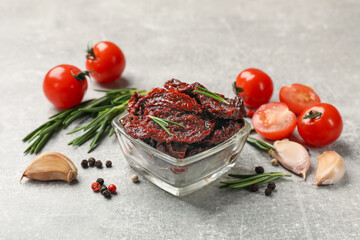 Delicious sun dried tomatoes, fresh vegetables, rosemary and garlic on light grey table
