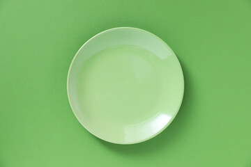 One empty plate on green background, top view