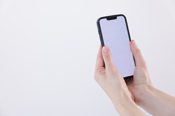 Woman holding smartphone with blank screen on white background, closeup. Mockup for design
