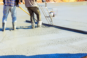 Contractor use screed to level freshly poured concrete on construction site in broad works day