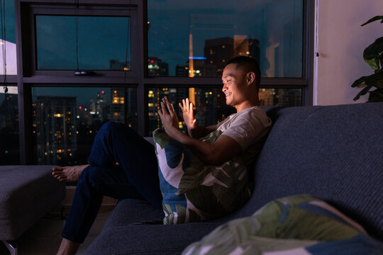 Young man video calling girlfriend on couch